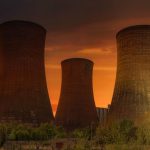 Atomic Aquatics - Exterior of huge cooling towers located in contemporary atomic power plant against bright setting sun under dramatic dark sky