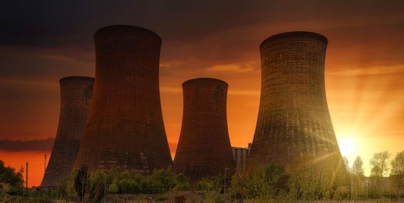 Atomic Aquatics - Exterior of huge cooling towers located in contemporary atomic power plant against bright setting sun under dramatic dark sky