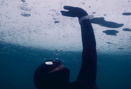 Wetsuit Cold - Anonymous diver in mask and wetsuit touching solid ice while swimming under seawater during freediving