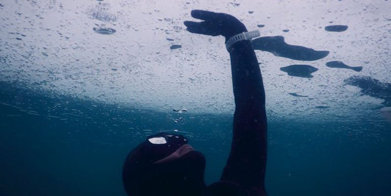 Wetsuit Cold - Anonymous diver in mask and wetsuit touching solid ice while swimming under seawater during freediving