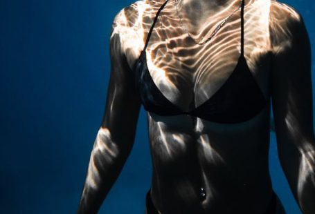 Dive Checklist - Underwater shot of fit young female in black bikini swimming in dark blue seawater with eyes closed