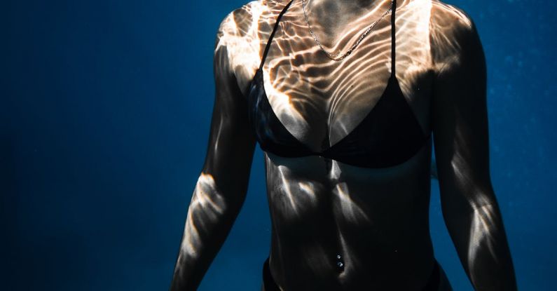 Dive Checklist - Underwater shot of fit young female in black bikini swimming in dark blue seawater with eyes closed