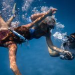 Underwater Communication - Group of young people with special equipment enjoying time together underwater with bubbles of oxygen