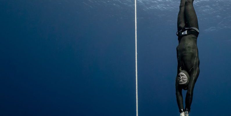 Conservation Diving - Full body of sporty male swimmer in black swimsuit diving in deep turquoise water of magnificent ocean