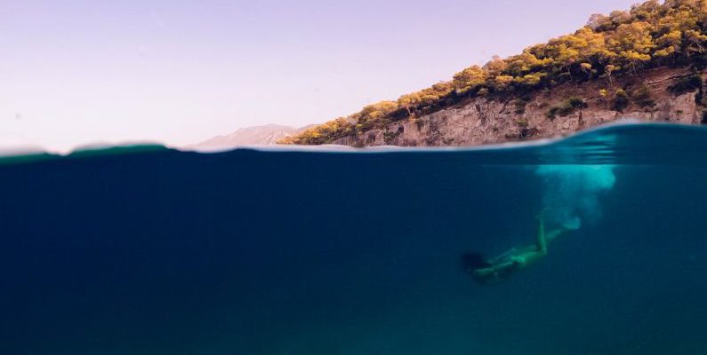 Thailand Diving - A person swimming in the ocean with a ball floating above them