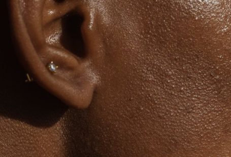 Ear Diving - Side view of crop face of anonymous African American lady with piercing in ear