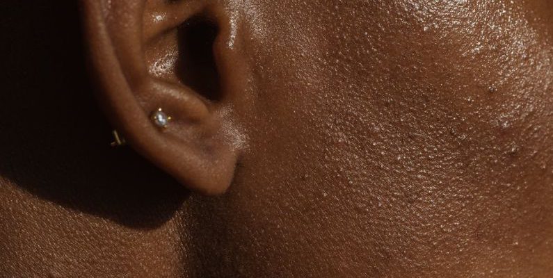 Ear Diving - Side view of crop face of anonymous African American lady with piercing in ear