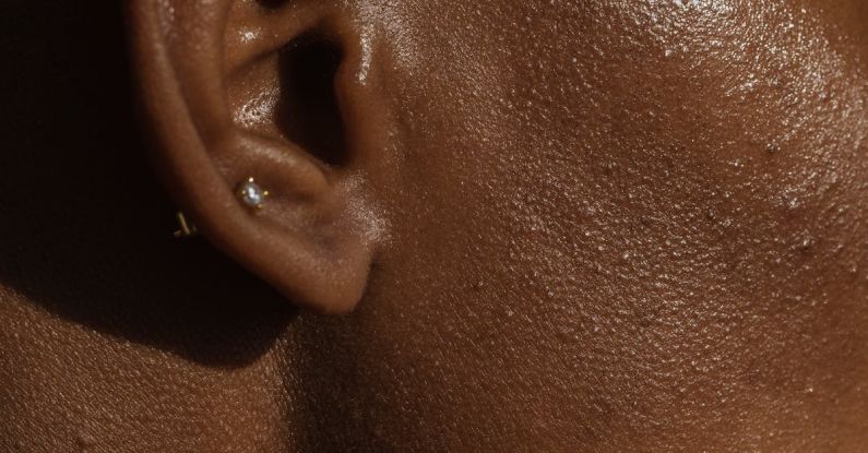 Ear Diving - Side view of crop face of anonymous African American lady with piercing in ear
