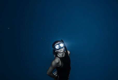 Night Diving - Unrecognizable woman diving in blue sea water
