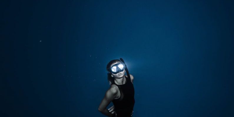 Night Diving - Unrecognizable woman diving in blue sea water