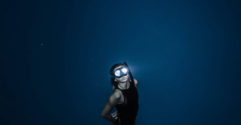 Night Diving - Unrecognizable woman diving in blue sea water